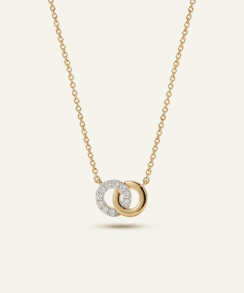 Gold necklace with interlocking rings pendant on a light beige background