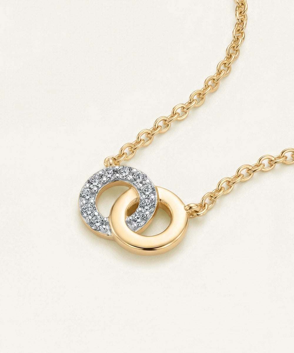 Gold necklace with interlocking rings and diamond accents on a light background
