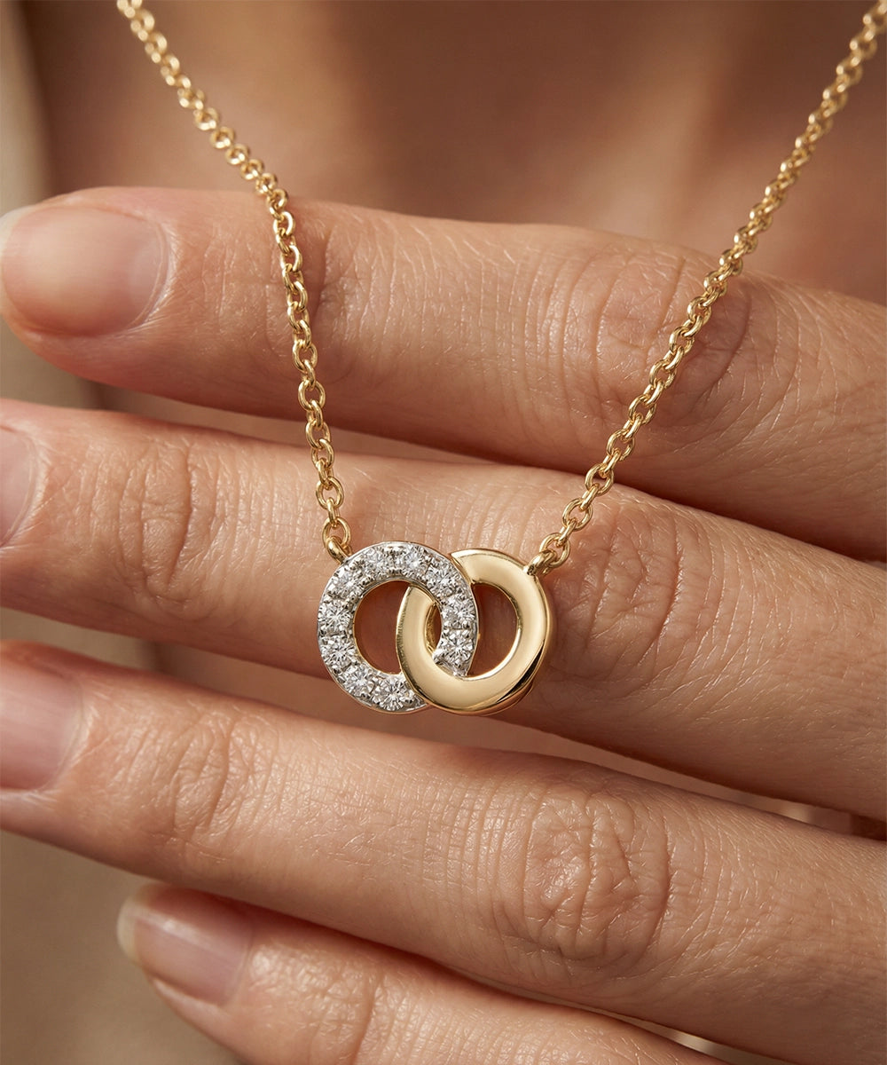 Gold necklace with interlocking rings held by a hand