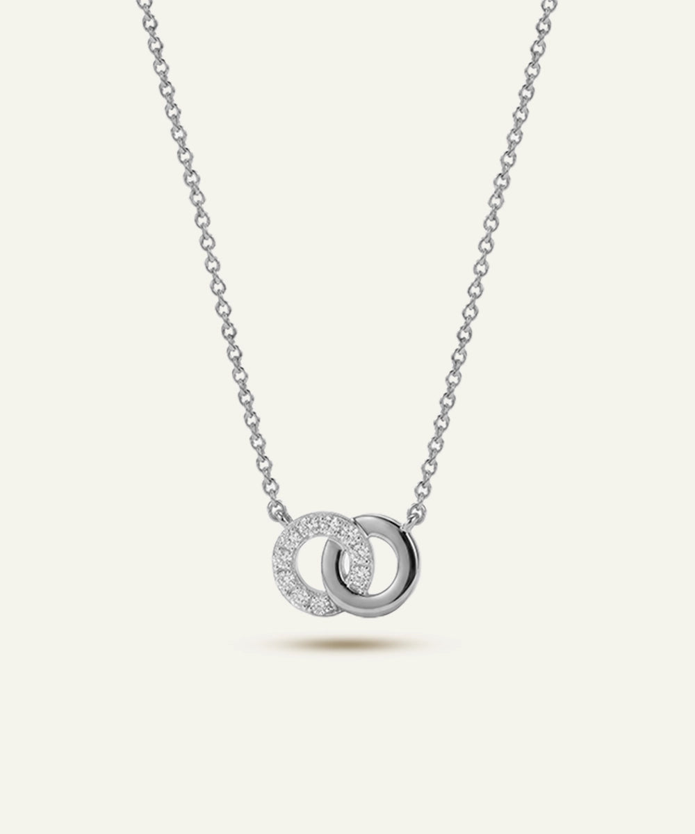 Silver necklace with interlocking rings pendant on a light gray background