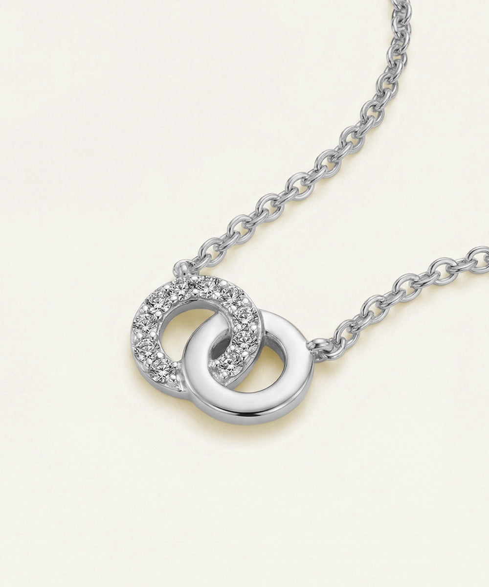 Silver necklace with interlocking rings on a light beige background