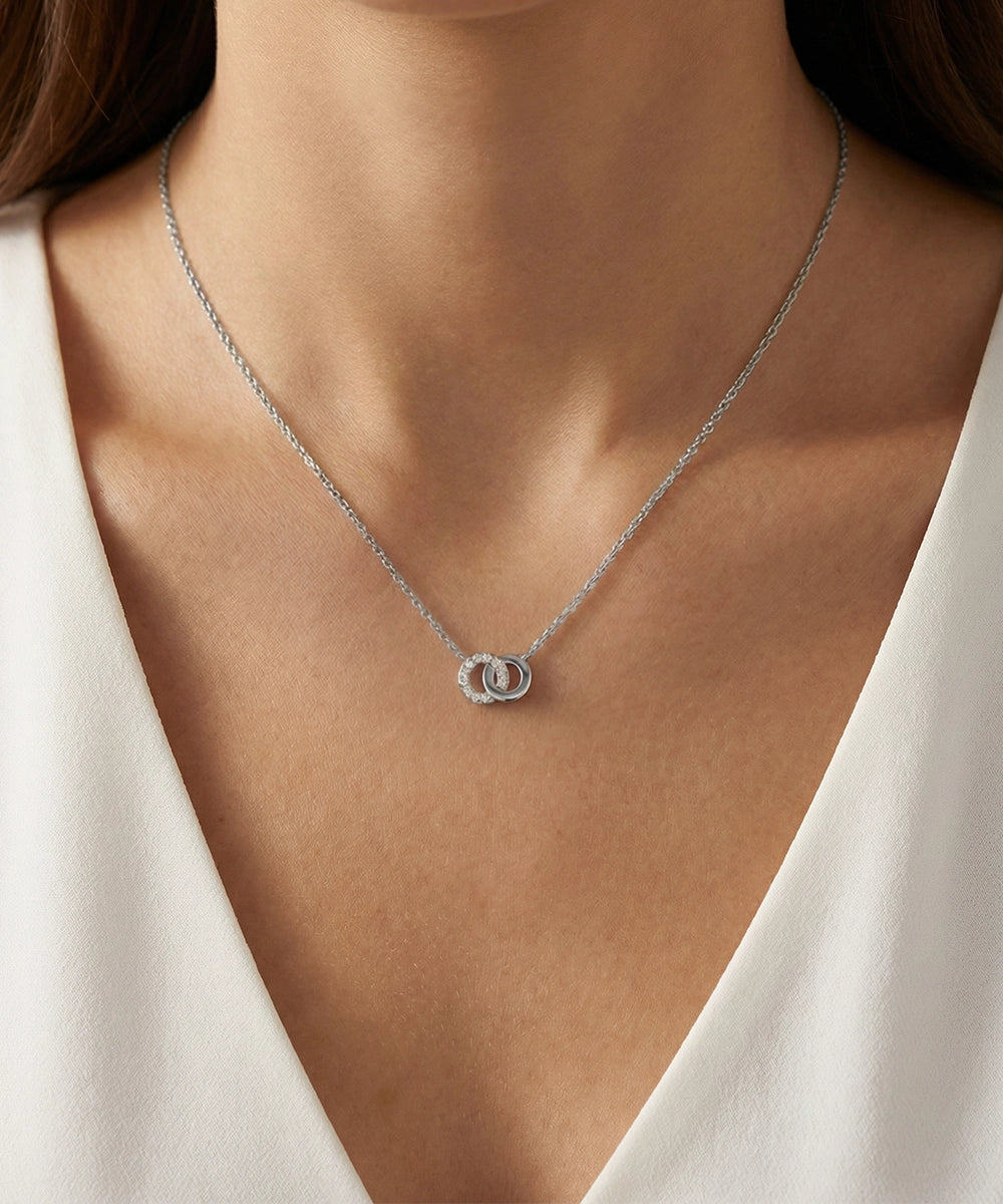 Silver necklace with a pendant on a person wearing a white top