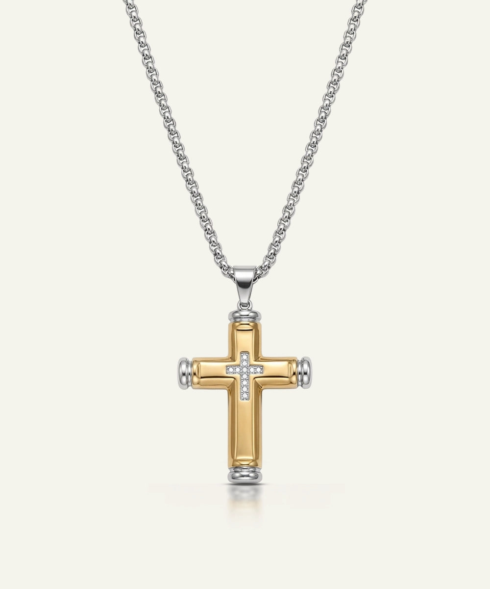 Gold and silver cross pendant on a chain against a white background