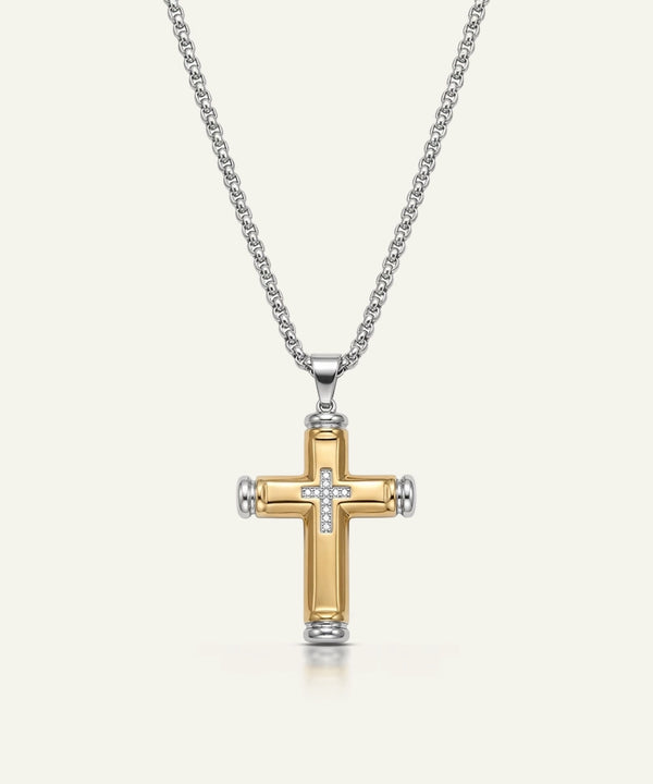 Gold and silver cross pendant on a chain against a white background