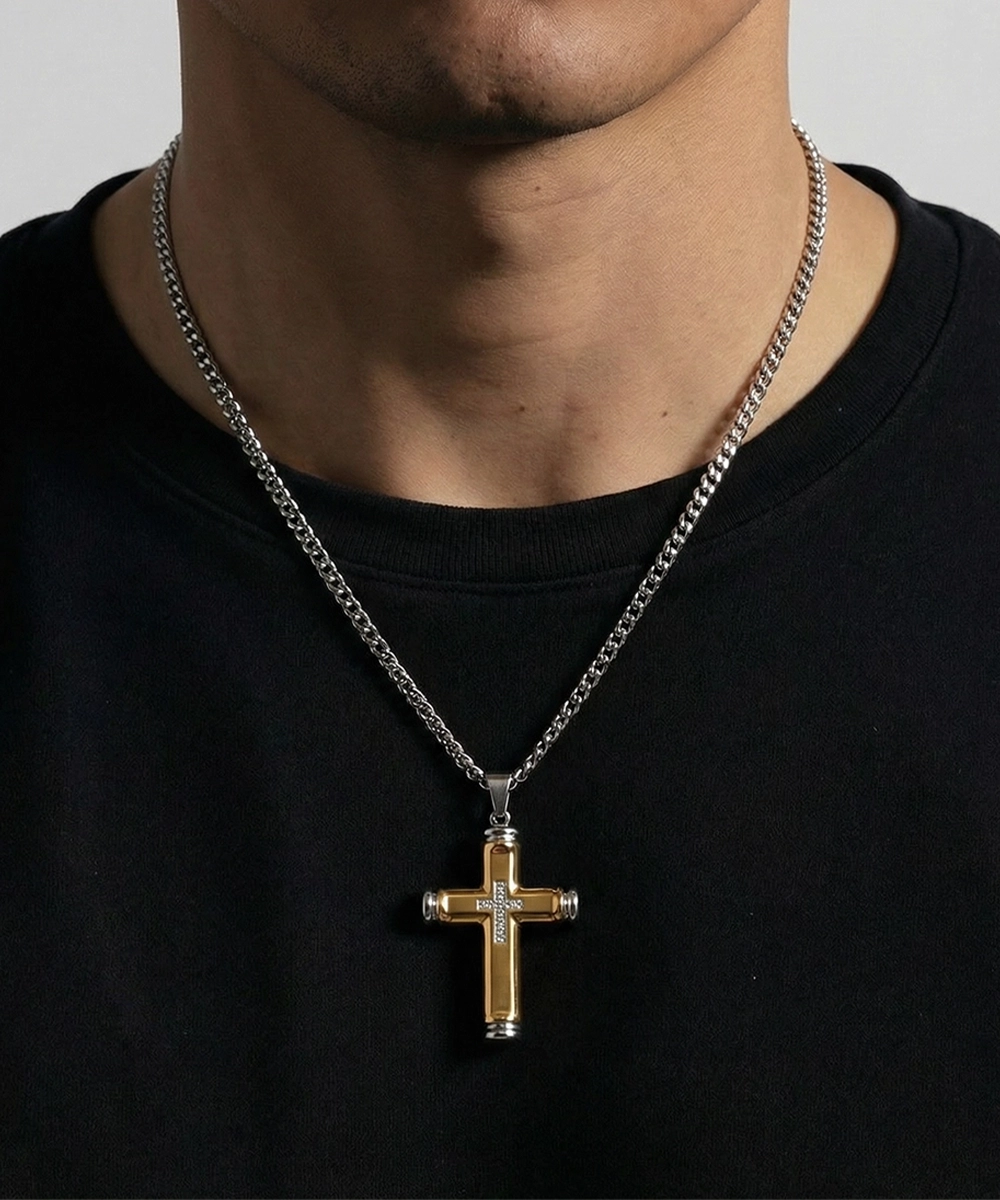 Man wearing a black shirt with a silver chain and cross pendant necklace.