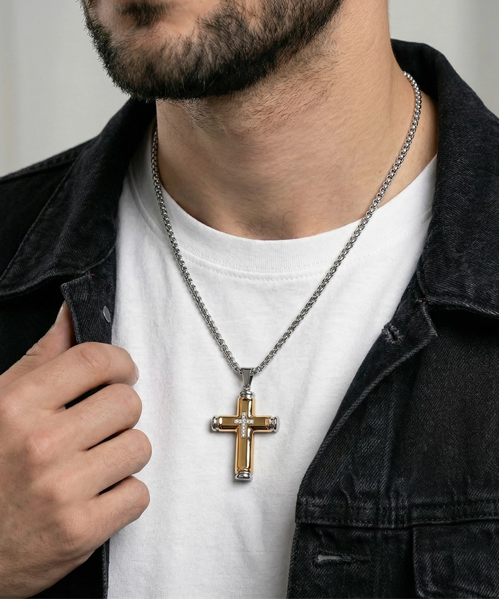 Man wearing a silver cross necklace with a white shirt and black jacket.