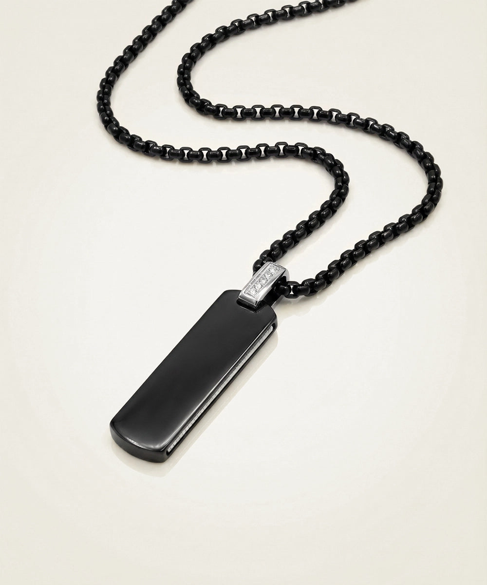 Black beaded necklace with a rectangular pendant on a light background