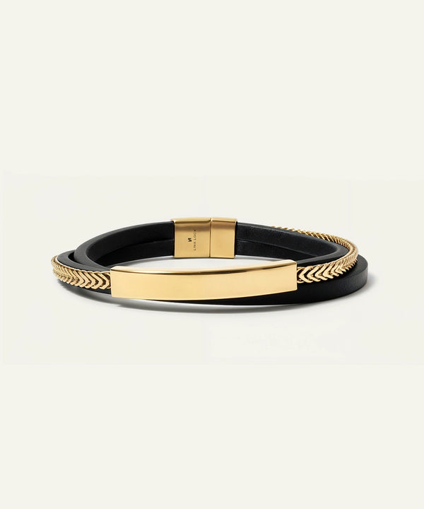 Black leather bracelet with gold accents on a light gray background