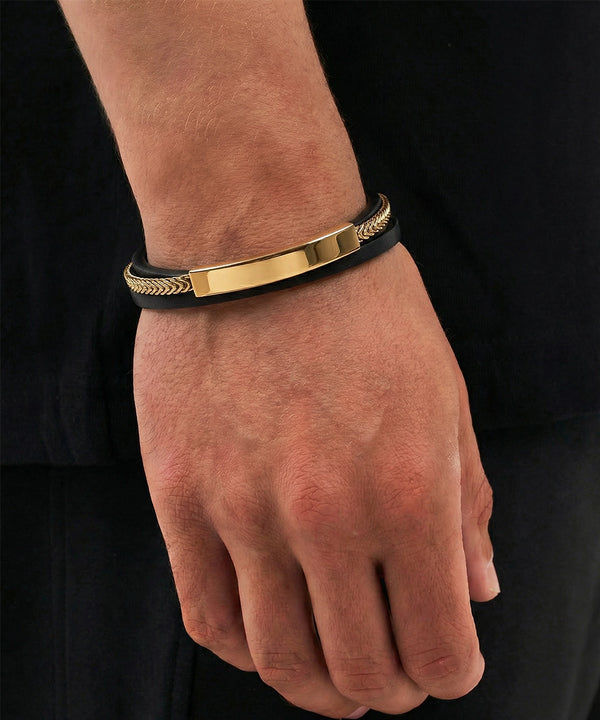 Gold and black bracelet on a wrist against a black background
