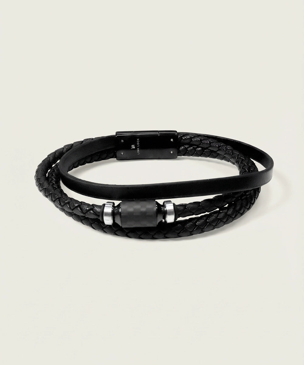 Black braided leather bracelet with metal accents on a light gray background