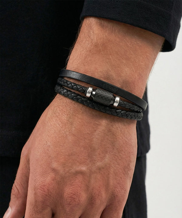 Black braided leather bracelet on a wrist with a neutral background