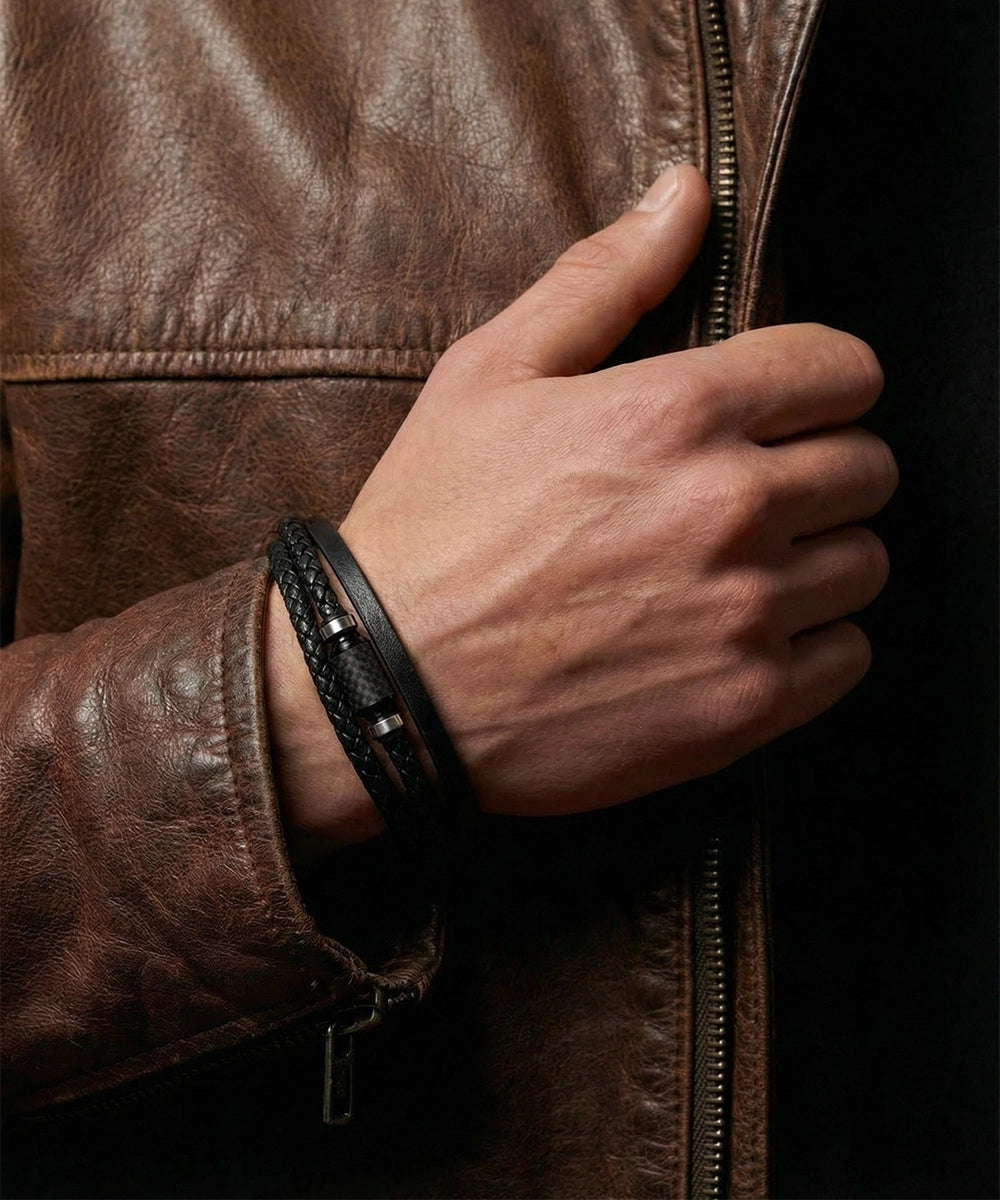 Hand wearing a black leather wristband on a dark background