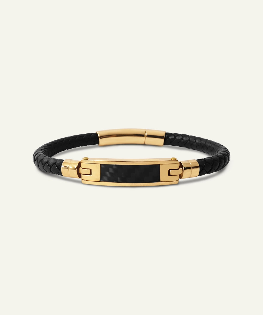 Black leather bracelet with gold accents on a white background