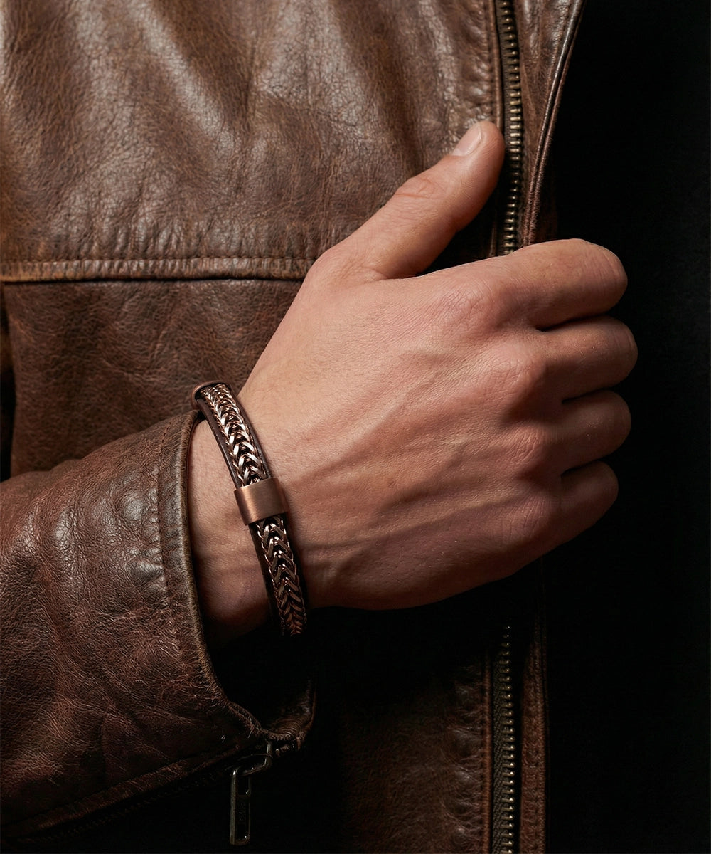 Hand wearing a brown leather bracelet with a dark background