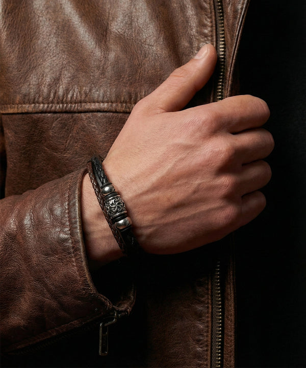 Hand wearing a leather bracelet on a dark background