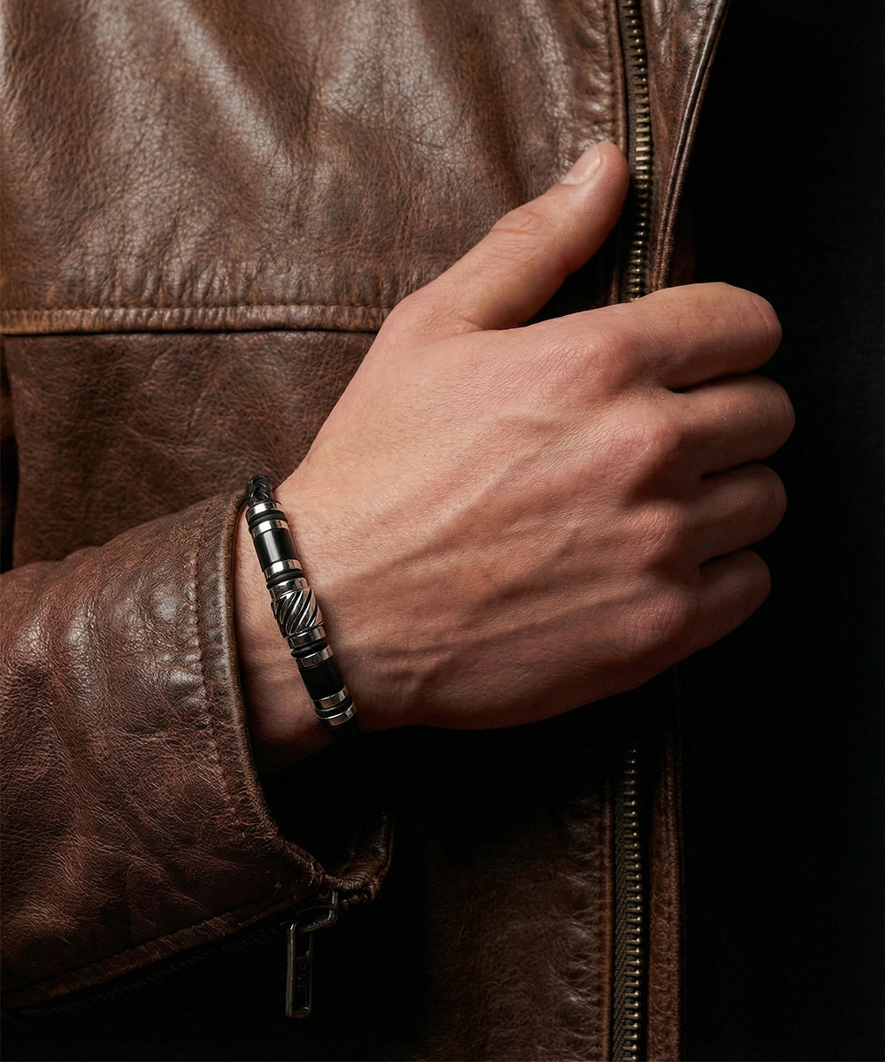 Hand wearing a silver bracelet on a brown leather jacket