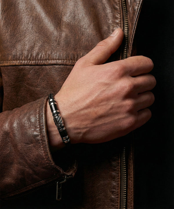 Hand wearing a silver bracelet on a brown leather jacket