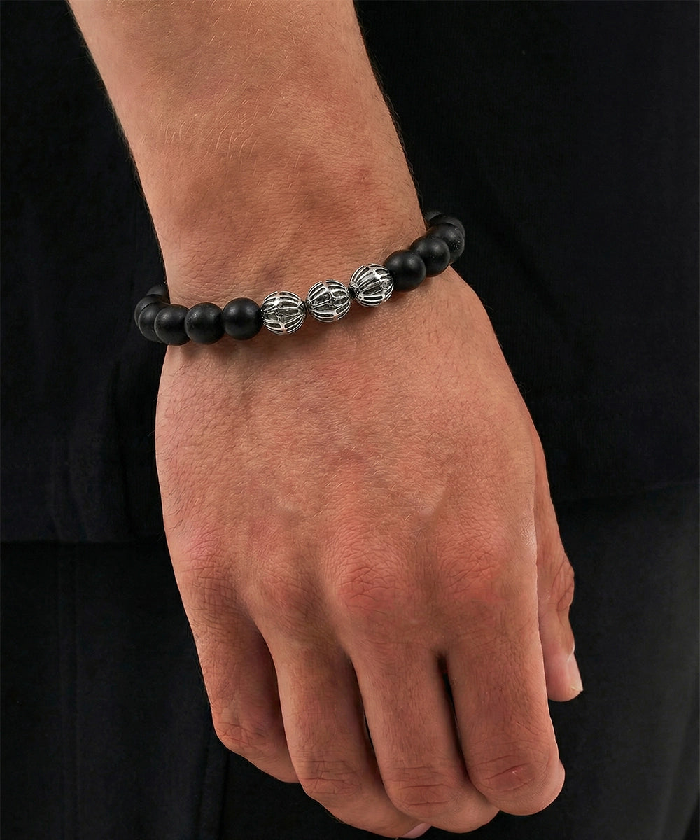 Black beaded bracelet on a wrist against a black background