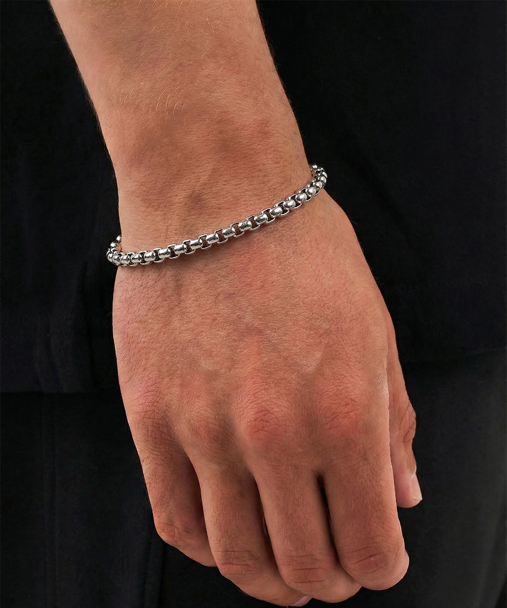 Silver bracelet on a wrist against a black background