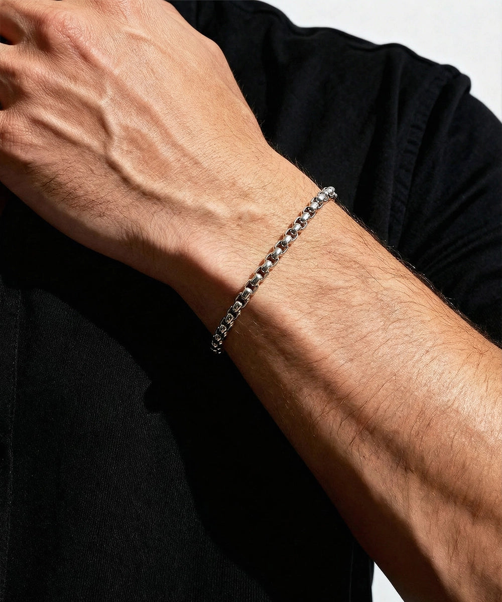 Close-up of a person's wrist wearing a silver bracelet against a black background