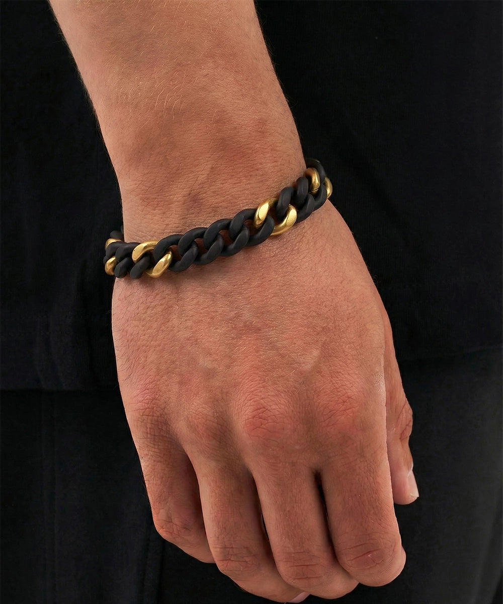 Hand wearing a black and gold braided bracelet on a black background