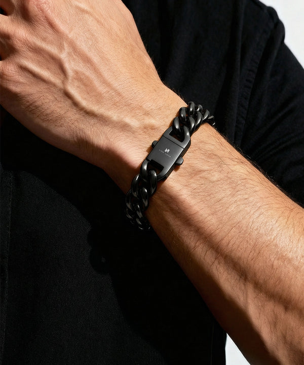 Black chain bracelet on a wrist with a neutral background