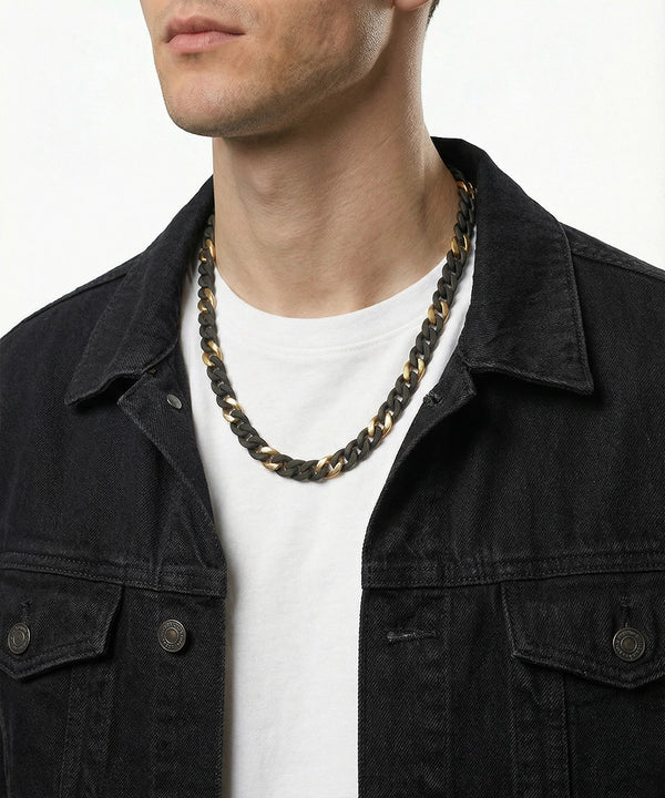 Man wearing a black and gold chain necklace with a white shirt and black jacket.