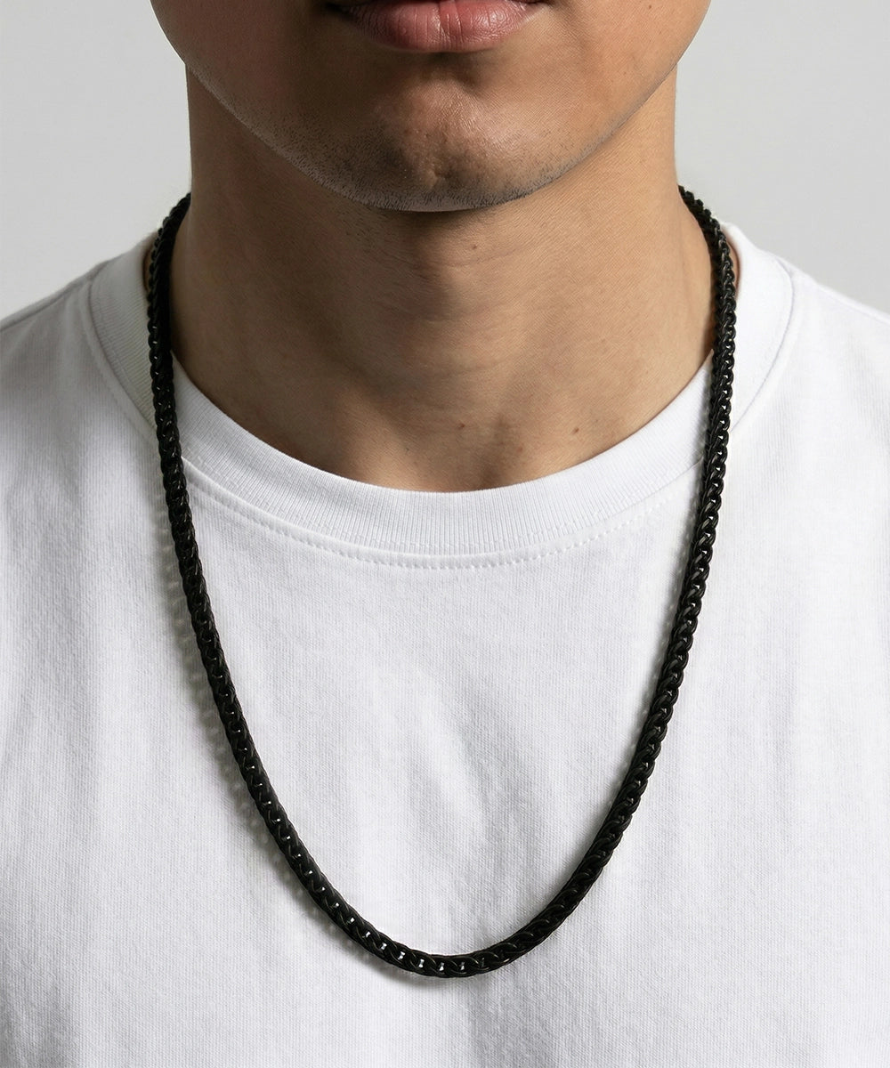 Person wearing a black beaded necklace on a plain background