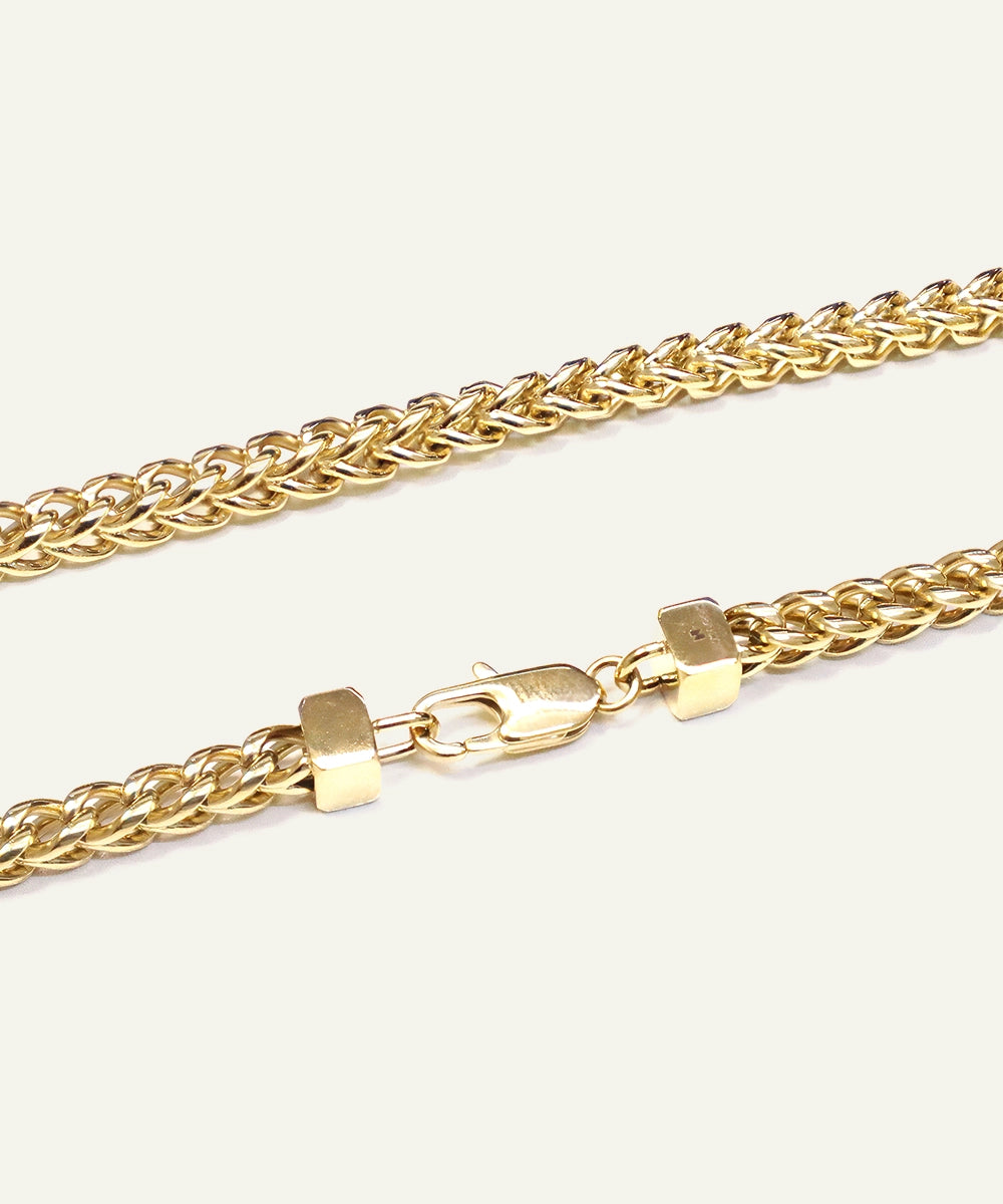 Gold chain necklace on a light beige background