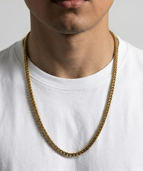 Gold chain necklace worn by a person on a white background