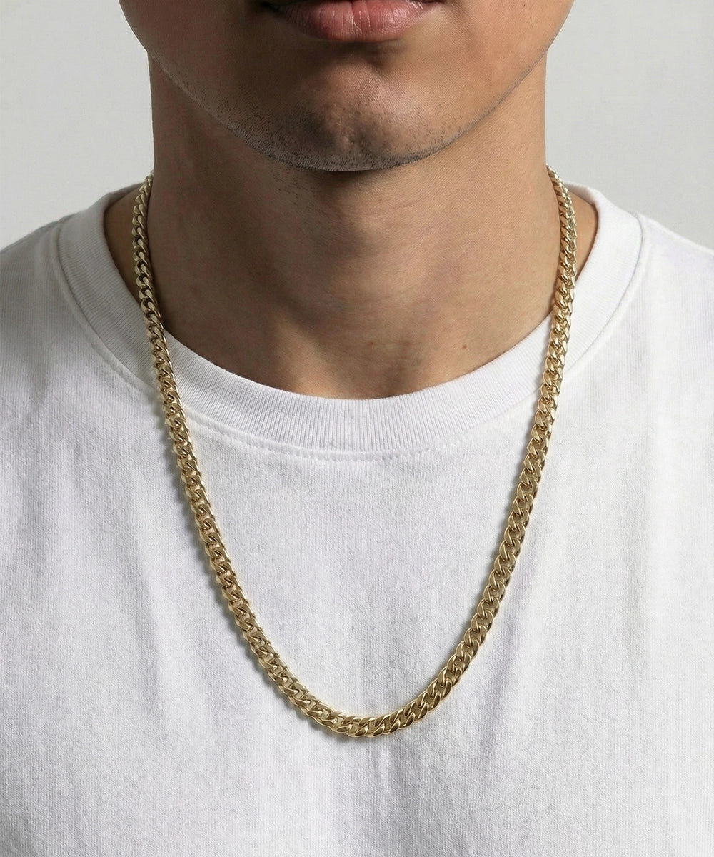 Person wearing a silver chain necklace on a plain background