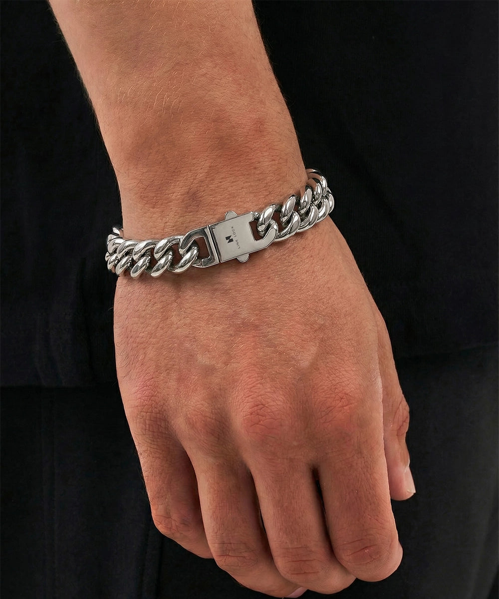 Silver chain bracelet on a person's wrist against a black background