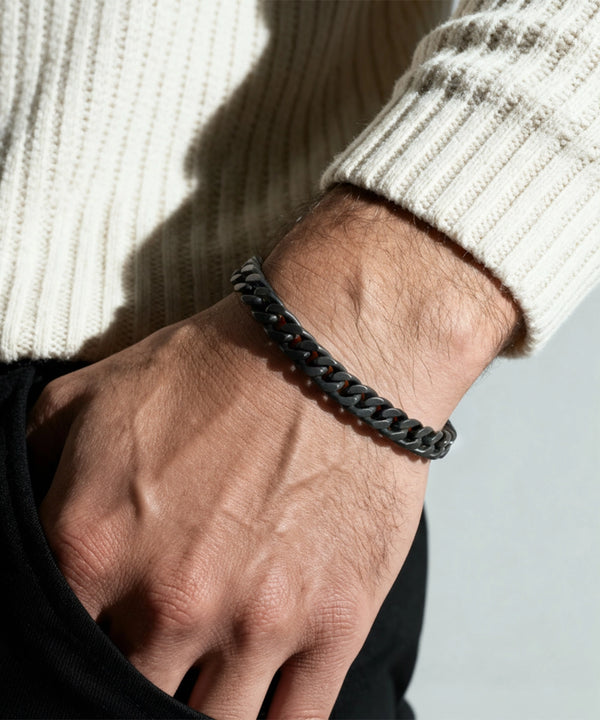 Black chain bracelet on a wrist with a neutral background