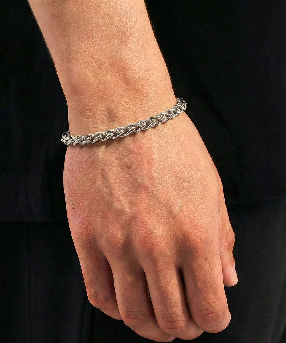 Silver braided bracelet on a person's wrist against a black background