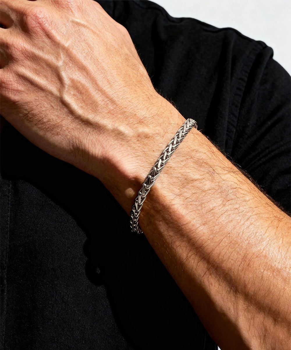 Silver chain bracelet on a person's wrist with a black shirt background