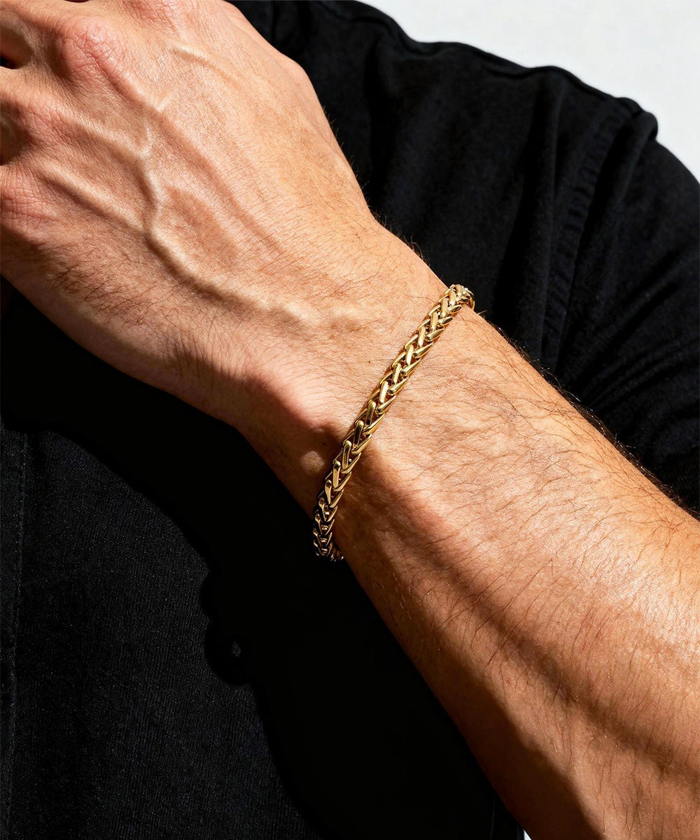 Gold chain bracelet on a person's wrist with a black background