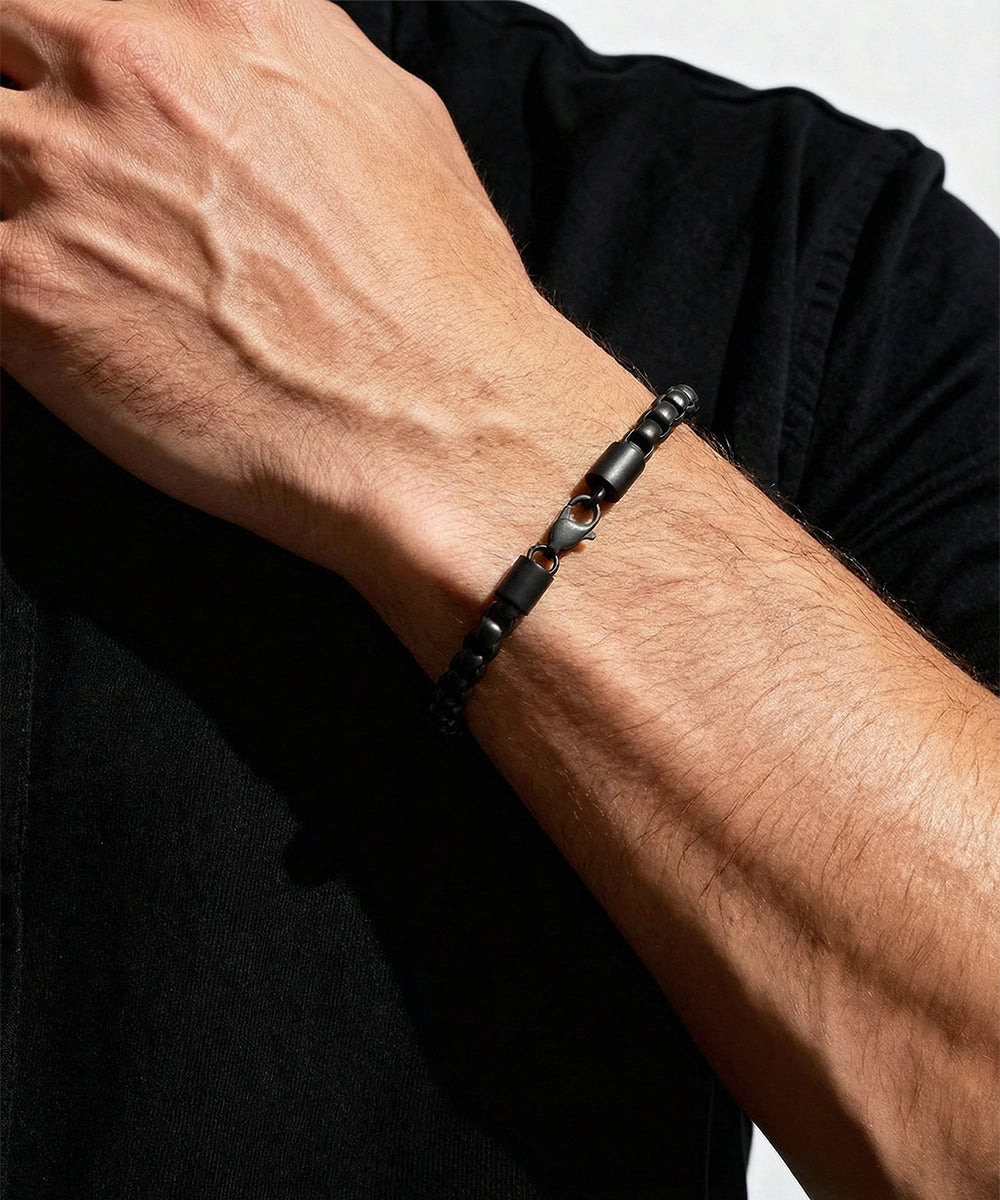 Black beaded bracelet on a wrist with a neutral background
