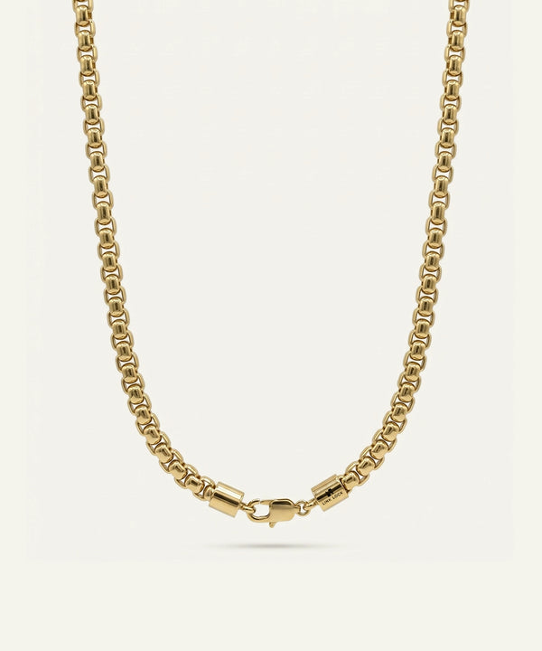 Gold chain necklace on a light beige background