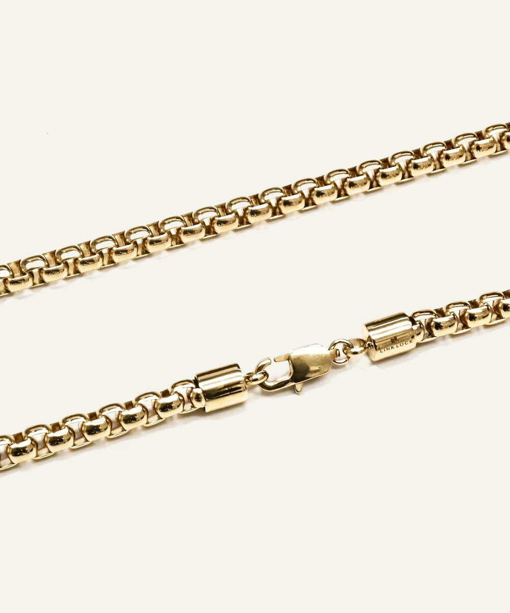 Gold chain necklace on a light beige background