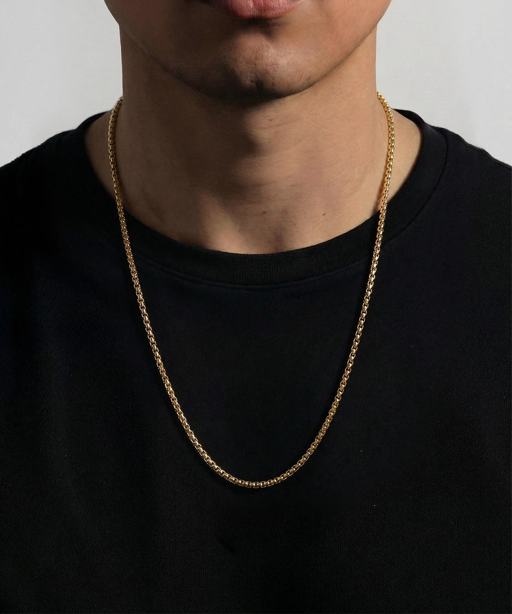 Person wearing a silver chain necklace against a plain background