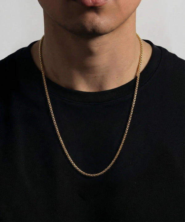 Person wearing a silver chain necklace against a plain background