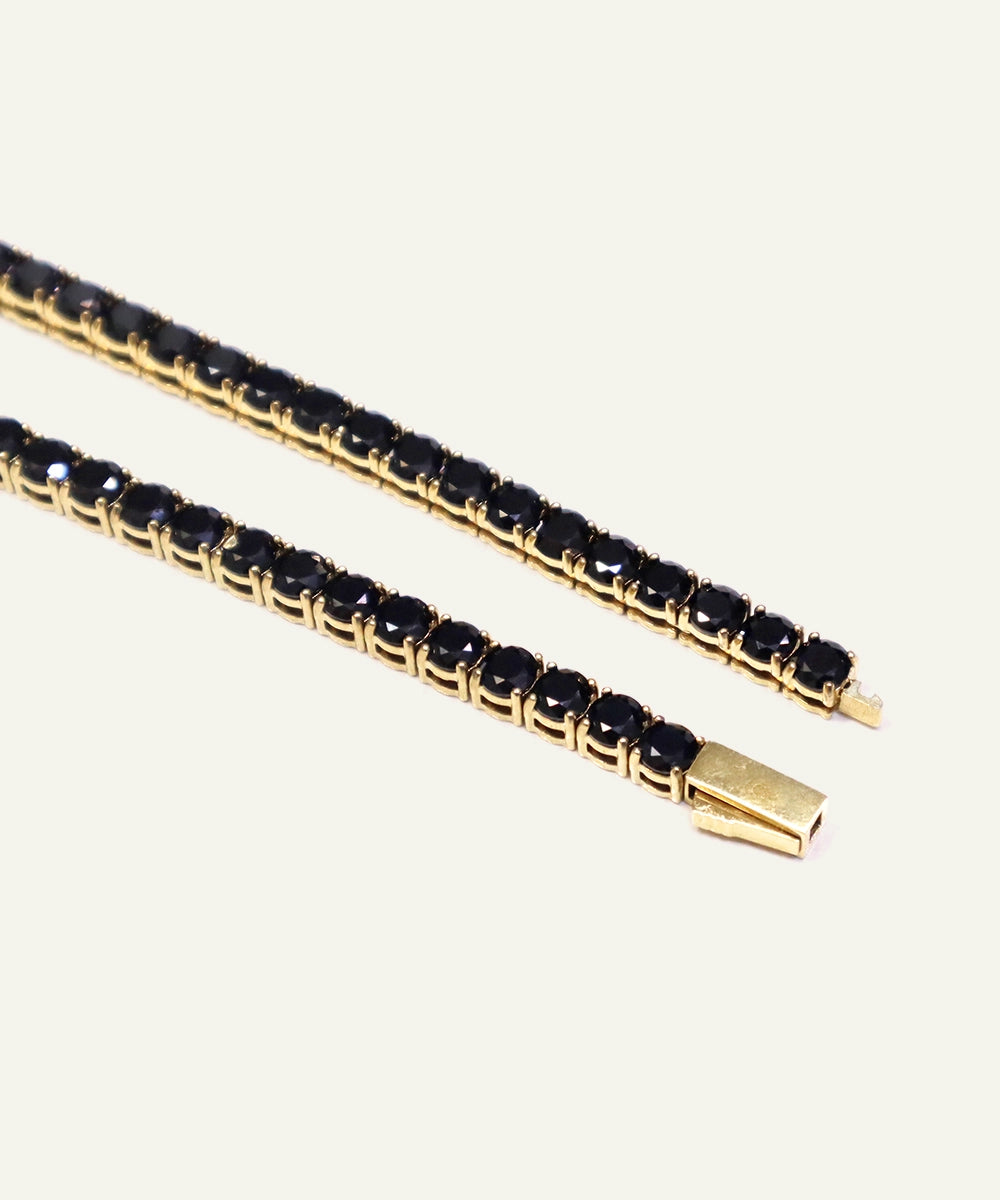 Gold bracelet with black stones on a white background