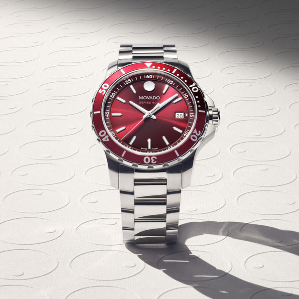 Silver watch with a red face on a textured white background