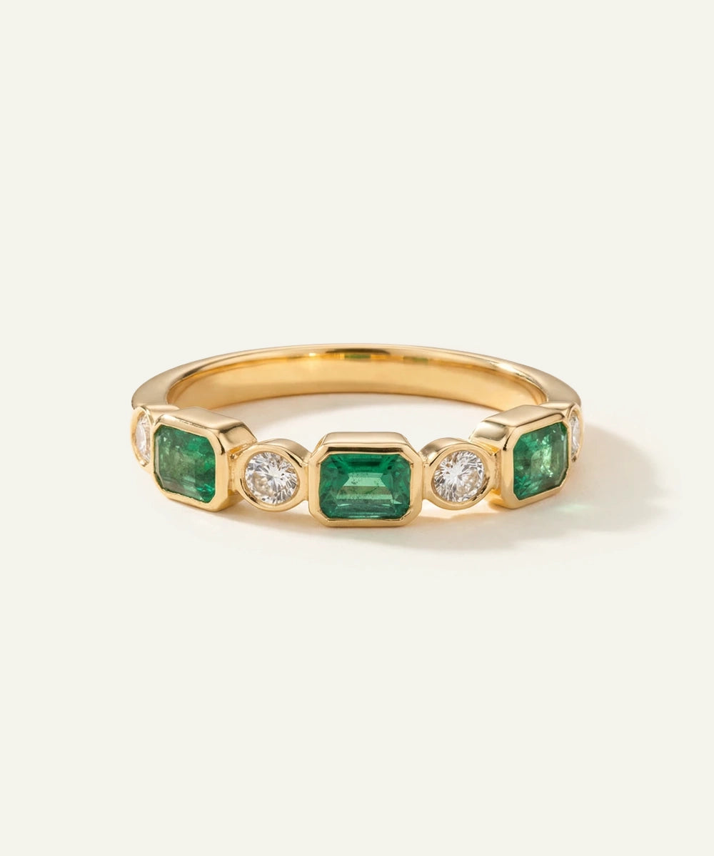 Gold ring with emeralds and diamonds on a white background