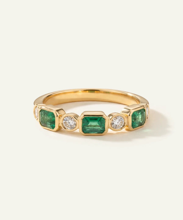 Gold ring with emeralds and diamonds on a white background