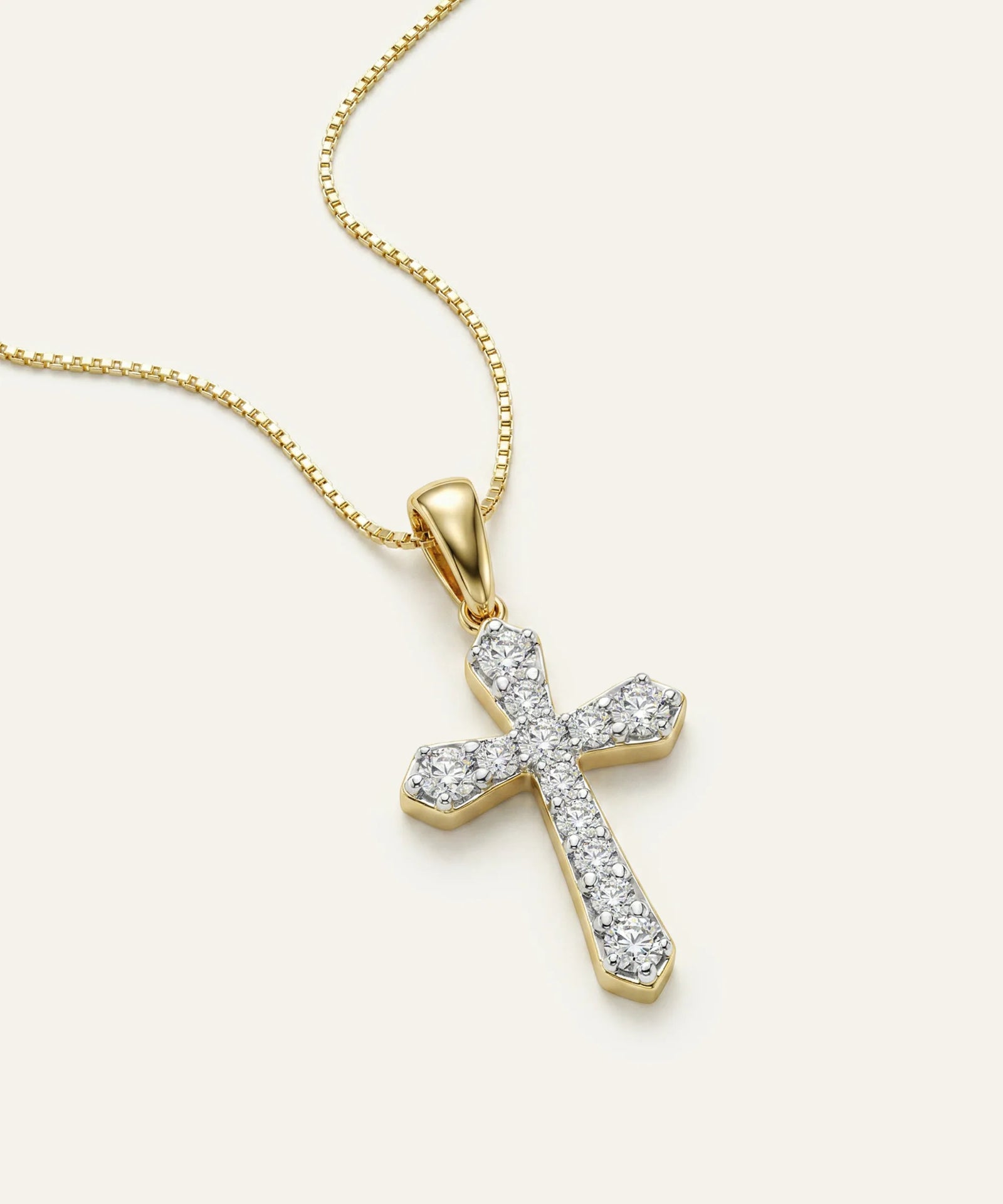 Gold cross pendant with diamonds on a white background
