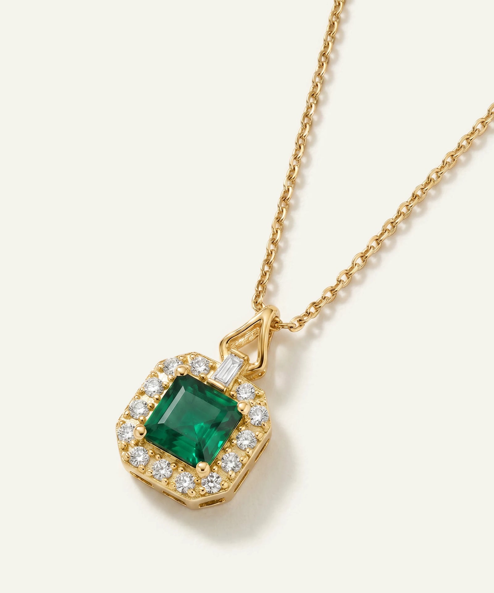 Gold necklace with a green gemstone pendant on a white background