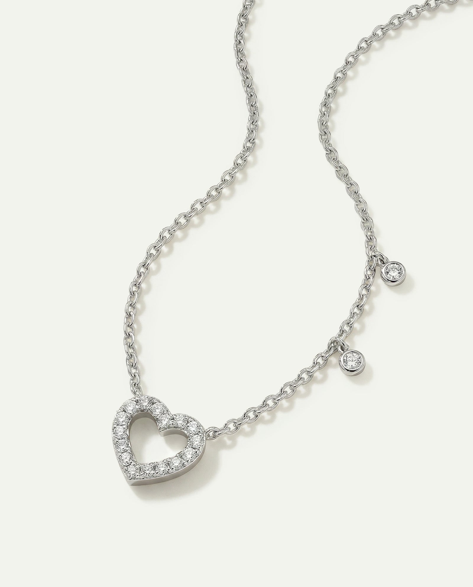 Silver necklace with a heart-shaped pendant on a light gray background