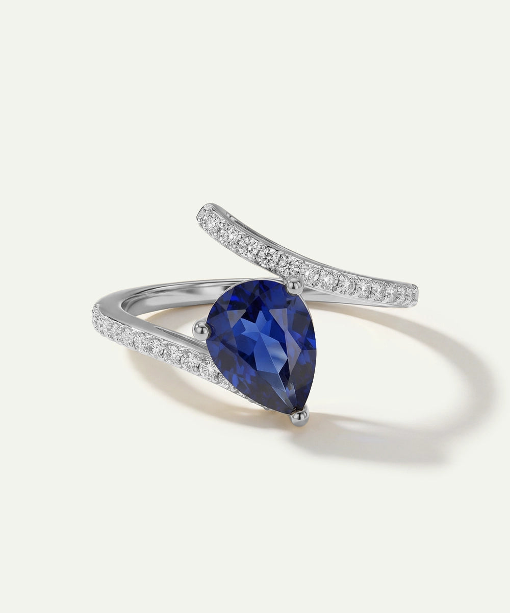 Ring with a blue gemstone and diamond-studded band on a white background
