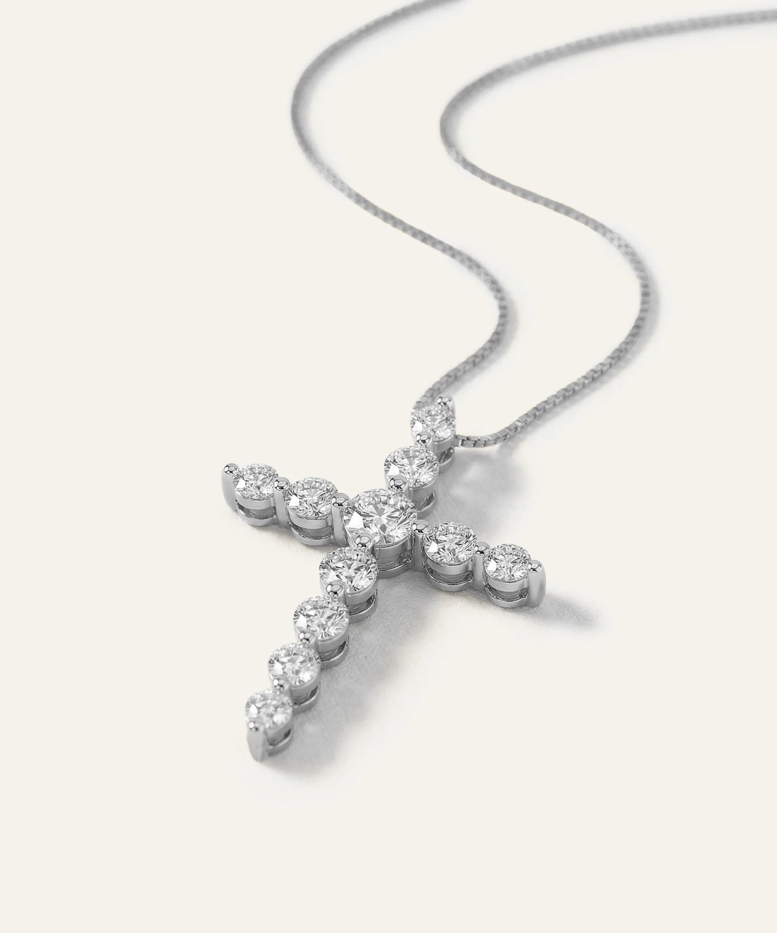 Diamond cross pendant on a chain against a white background